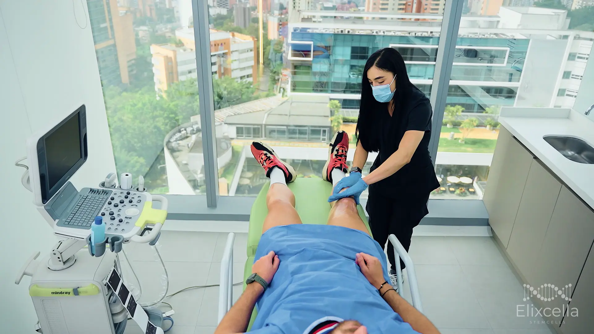 Patient receiving ultrasound-guided stem cell treatment at Colombia Care with Medellín city view
